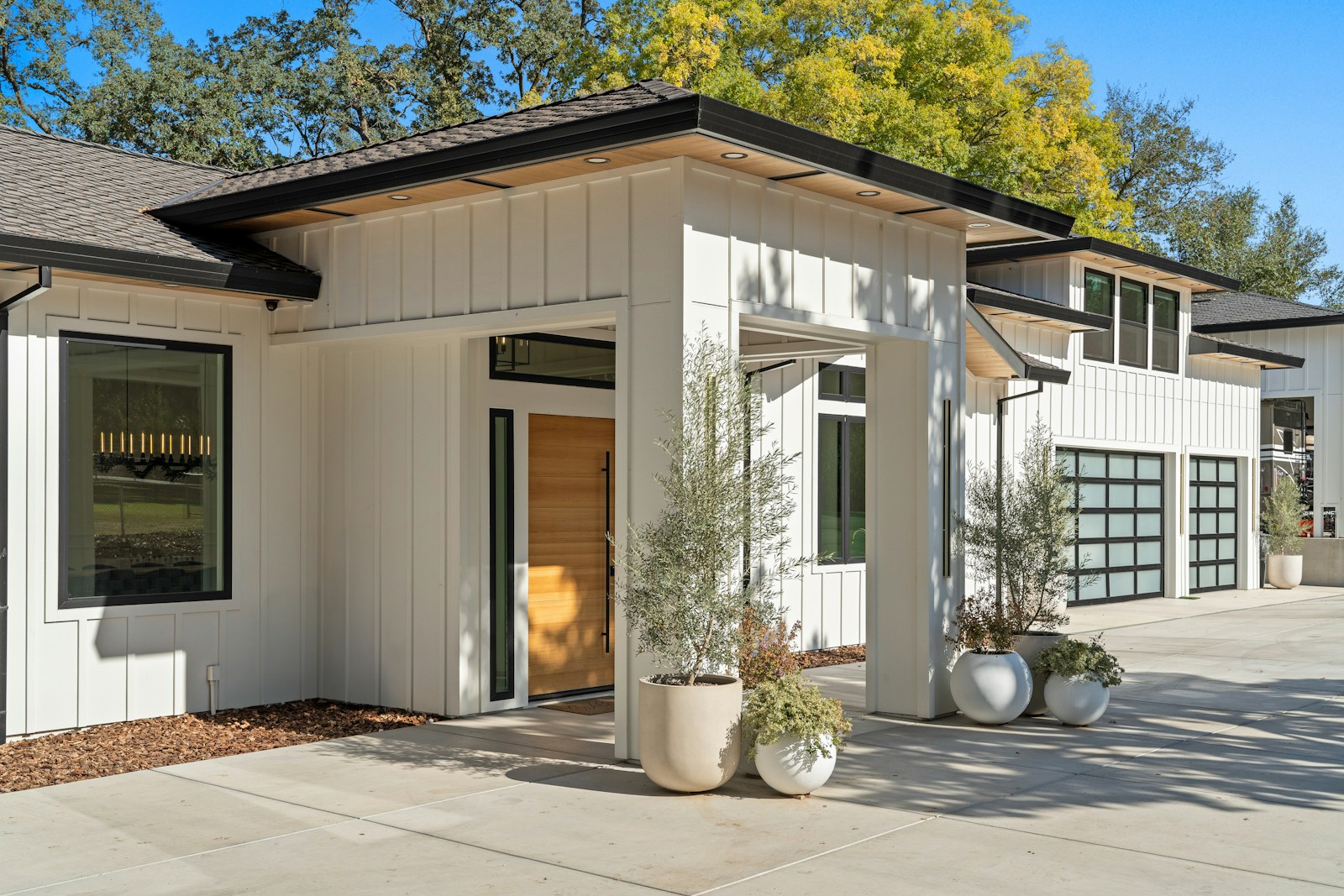 A modern white home with large windows, garage doors and landscaped entry